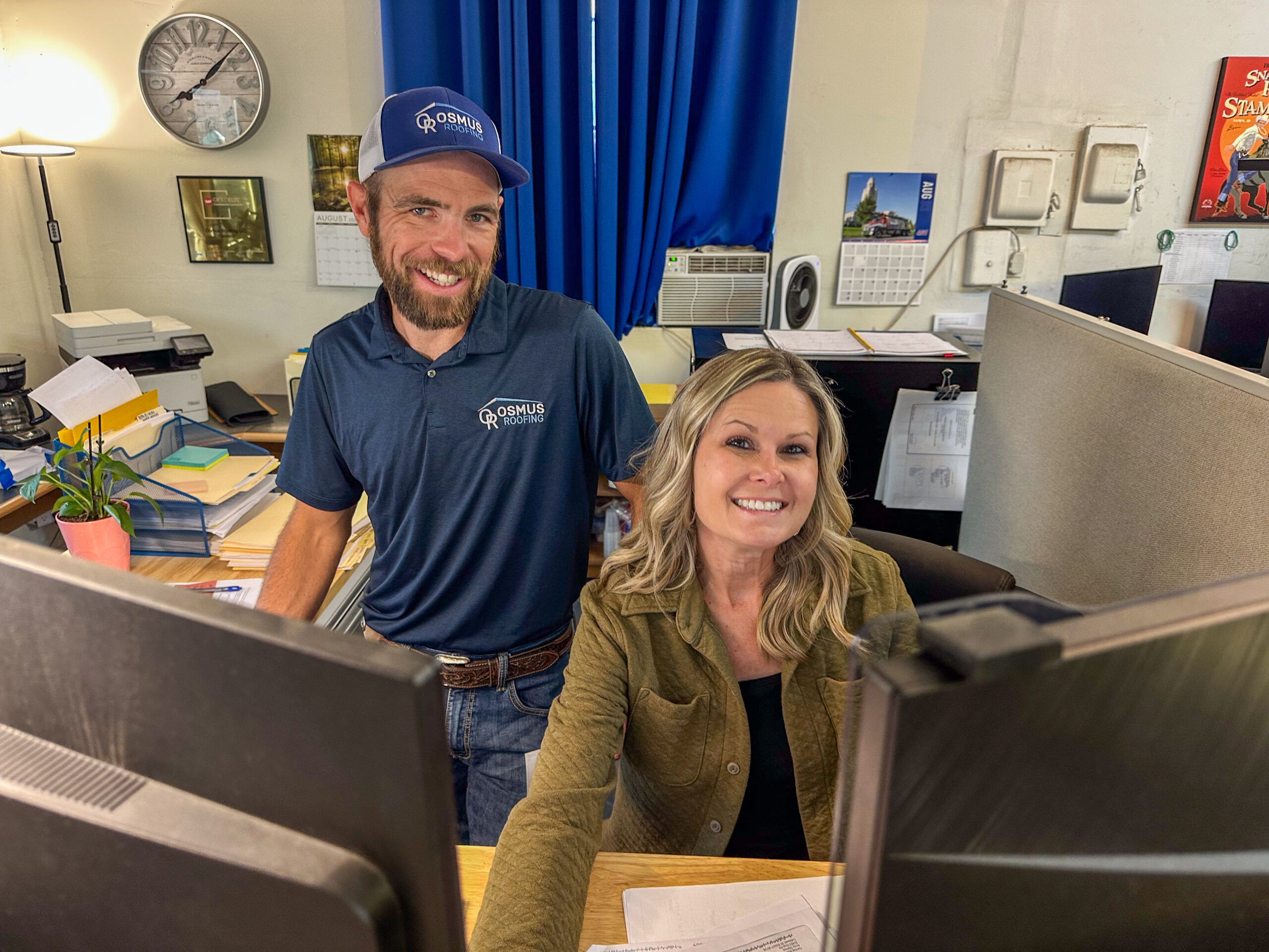 Osmus-Jenn-Josh-Working-Office-003 Two office admins ready to schedule a roofing consultation with Osmus Roofing.