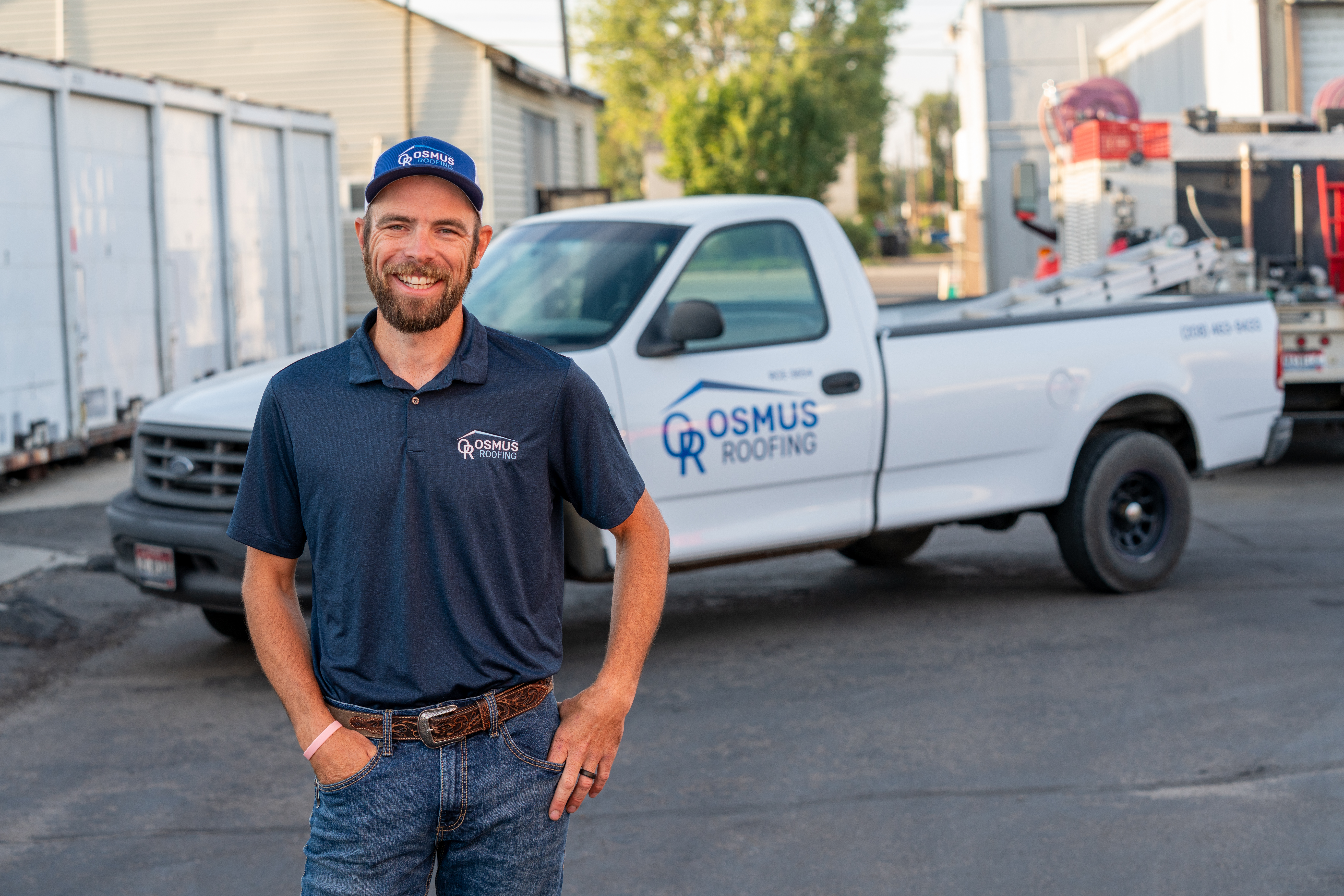 Osmus Roofing manager standing in front of a branded Osmus Roofing white truck.